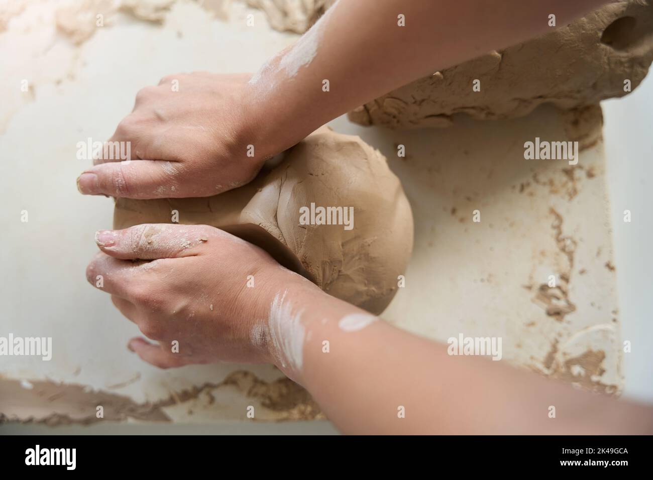Craftswoman inginocchia un pezzo di argilla con le mani sul tavolo Foto Stock