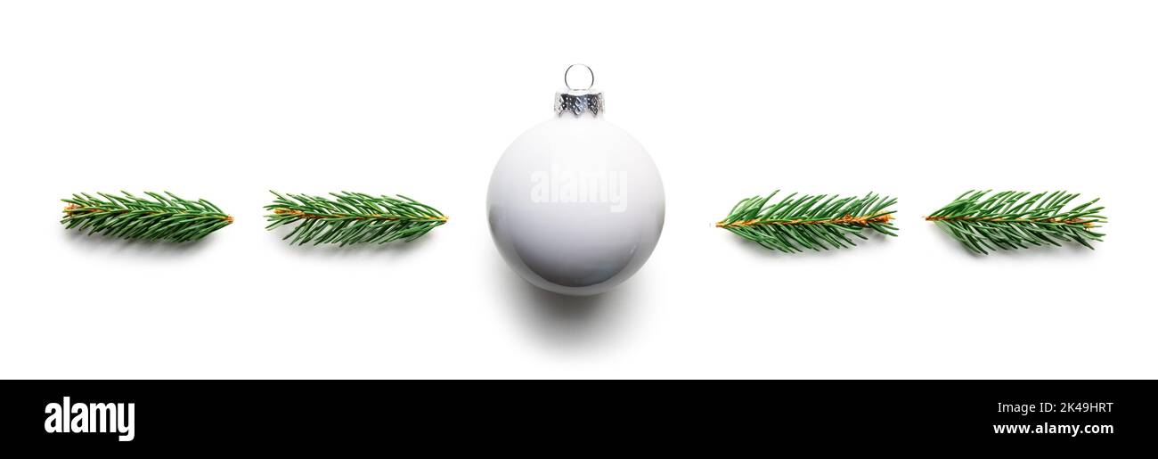 Sfondo Natale creativo con palla di Natale bianco e ramoscelli di pino isolato su sfondo bianco. Disposizione piatta, vista dall'alto, spazio di copia Foto Stock