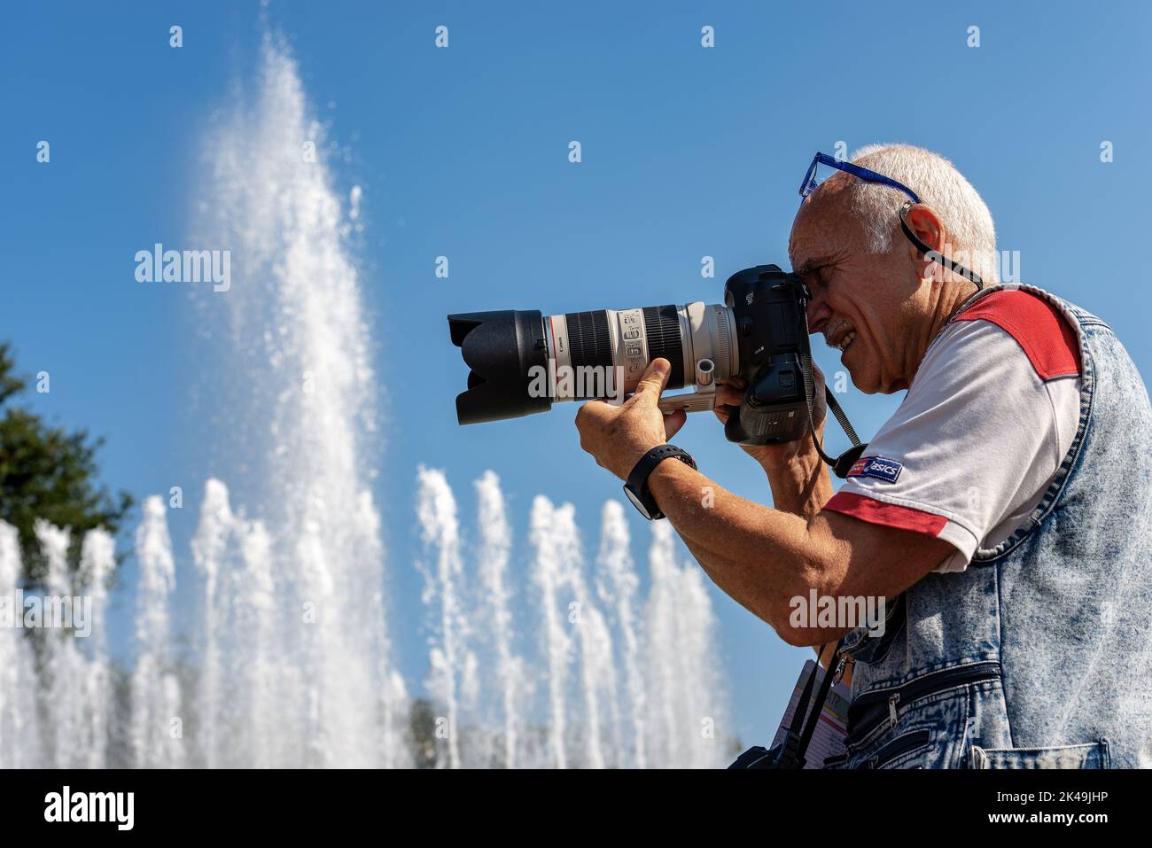 Fotografo con attrezzatura professionale (Canon EOS Mark III) mentre sta effettuando un servizio fotografico nel centro di Milano di fronte al Castello Sforza, Foto Stock