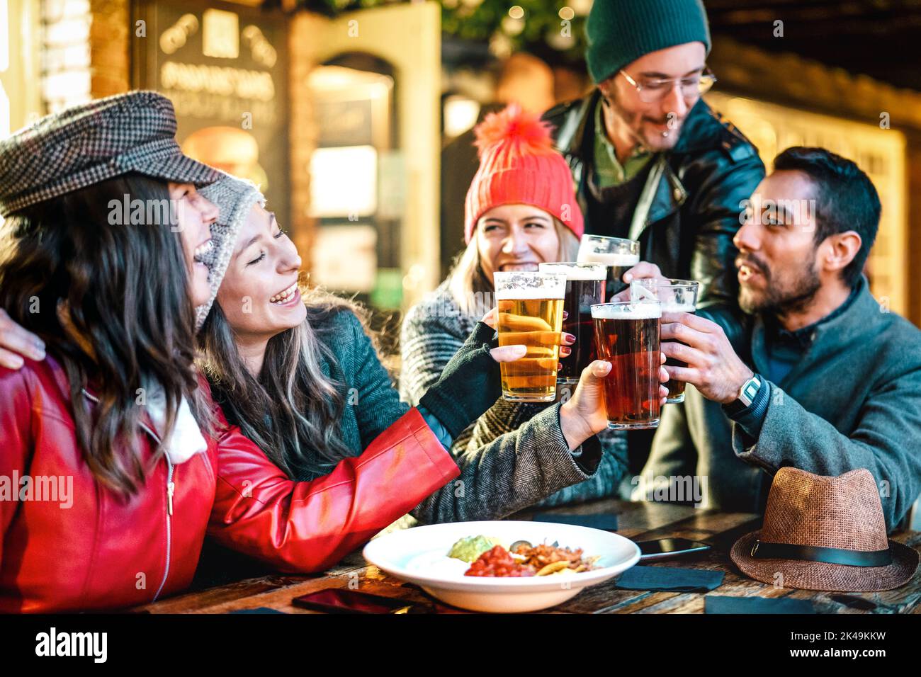 Amici multiculturali felici bevendo birra con nachos all'aperto di notte - concetto di stile di vita di cibo e bevande sui giovani che si godono il tempo insieme o Foto Stock