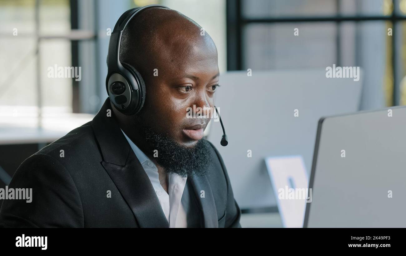 Responsabile adulto impegnato marketing specialista ingegnere software indossando cuffie che lavorano sul laptop utilizzando app internet e-mail online focalizzato africano Foto Stock