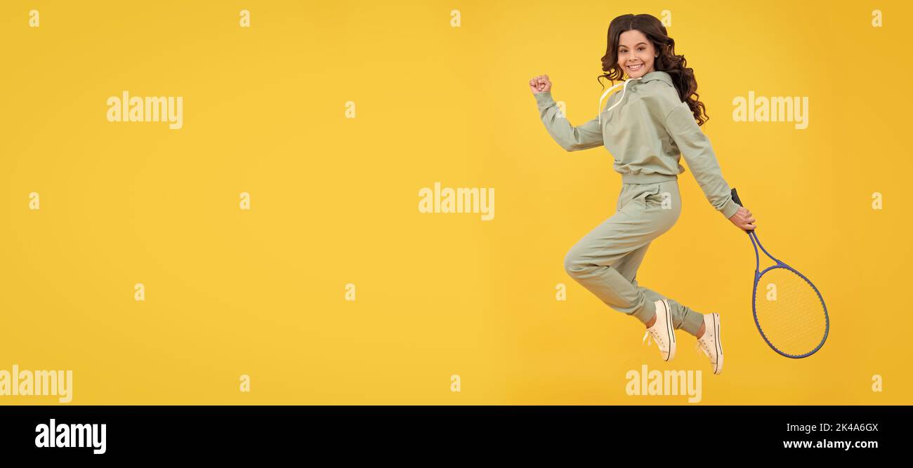 felice energico bambino salto in sportswear con racchetta da squash su sfondo giallo, successo sportivo. Poster orizzontale della faccia figlio isolata, banner Foto Stock