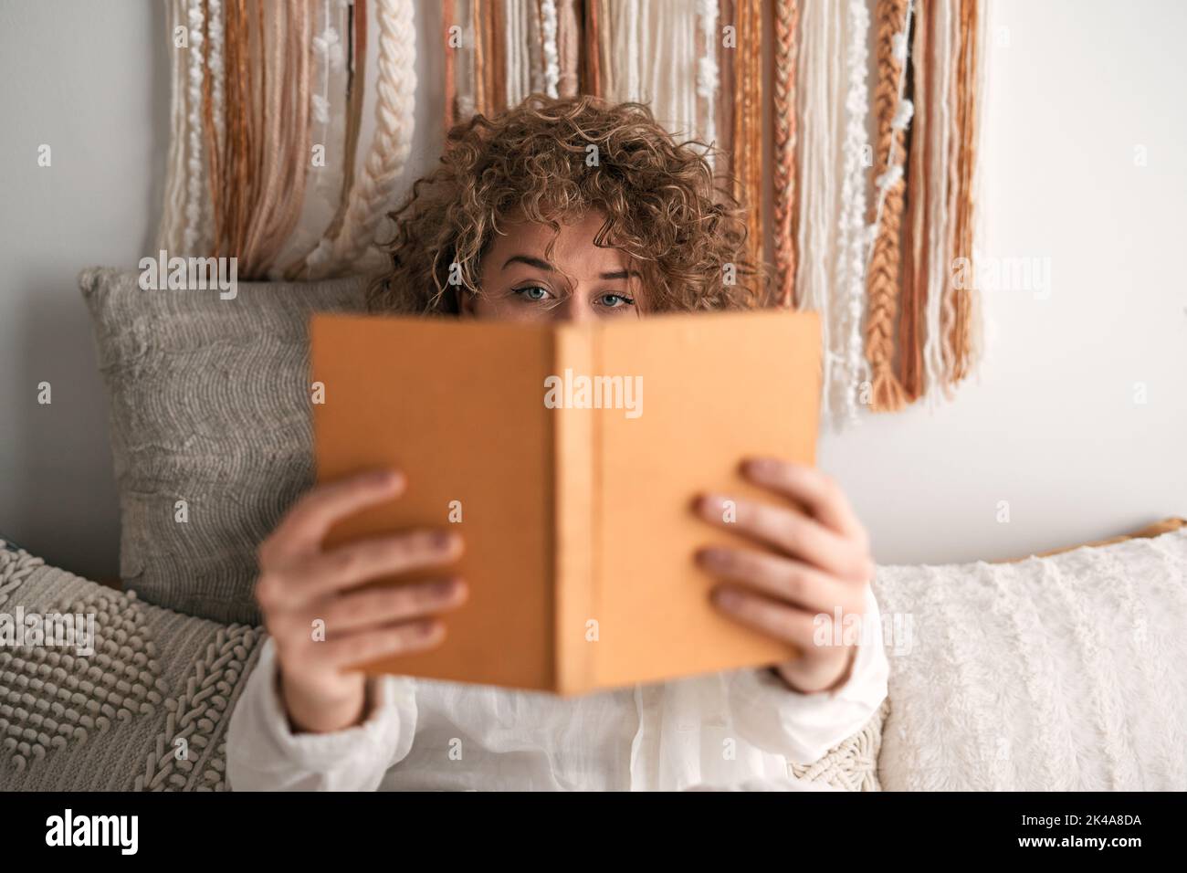Donna che sbirciava da dietro il libro Foto Stock