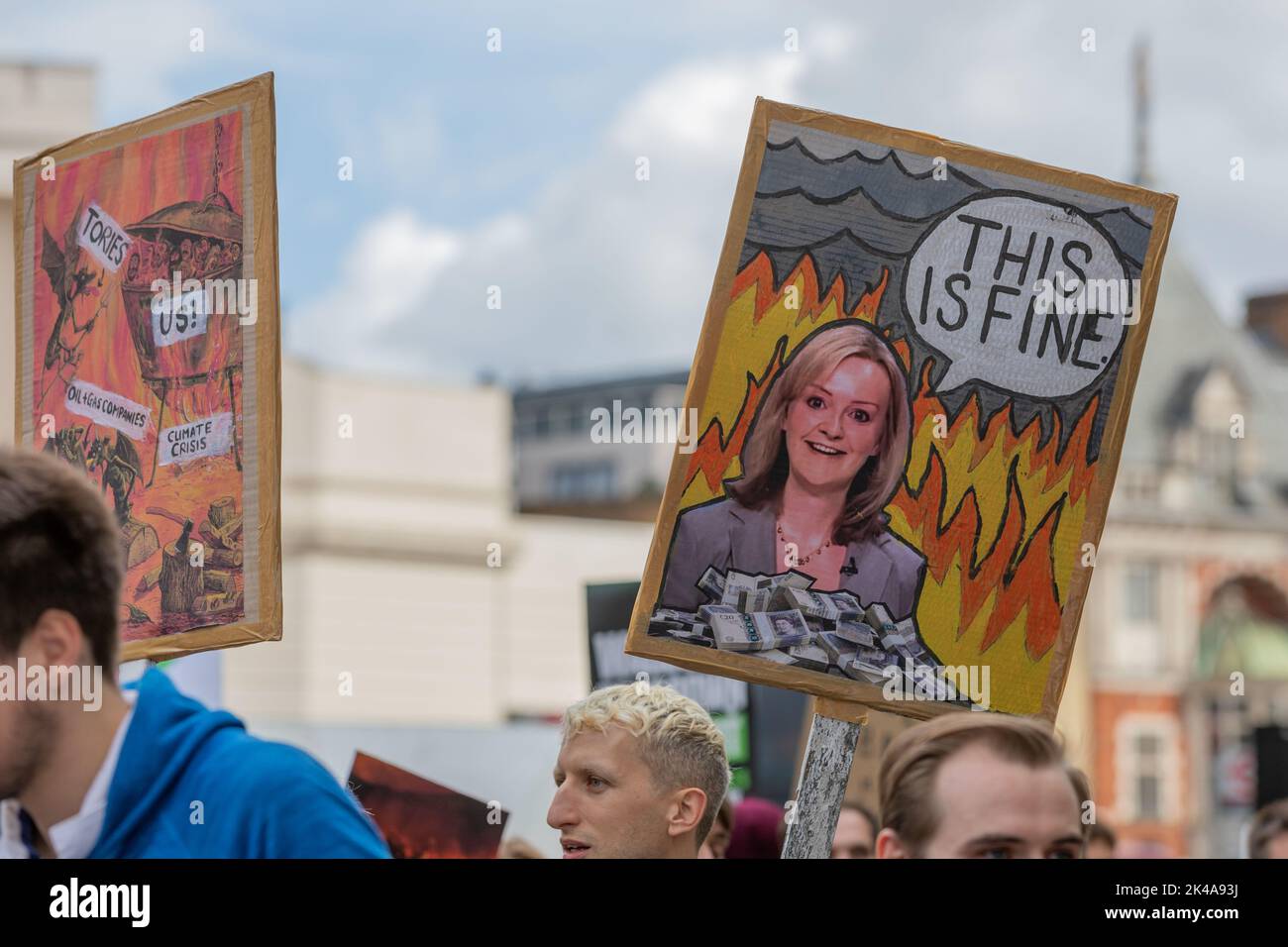 Londra, Regno Unito. 1 ottobre 2022. I manifestanti a Londra tengono cartelli illustrati durante una manifestazione pubblica. Un segno presenta una caricatura di una donna politica circondata da fiamme e denaro, che fa riferimento al meme “This is fine” per evidenziare la percezione di compiacenza politica in mezzo alla crisi. Un altro cartello evoca temi distopici con slogan come "GUARDA SU di noi!" E "CONSUMARE". Il gruppo ambientalista ha appena fermato la protesta di Oil per le strade di Londra. Penelope Barritt/Alamy Live News Foto Stock