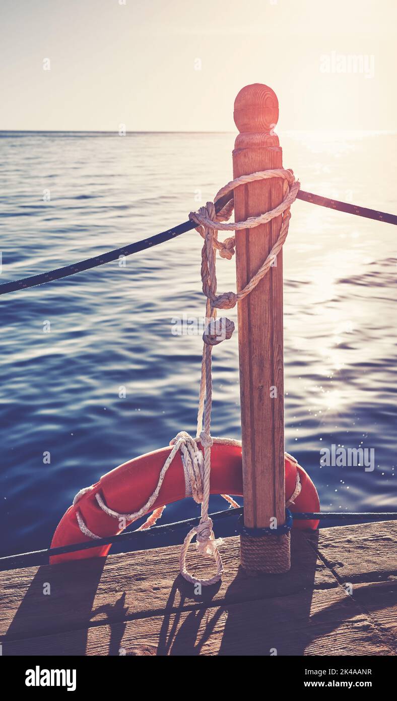 Lifebuoy ad un molo di legno contro il sole di tramonto, tonalità di colore applicato. Foto Stock