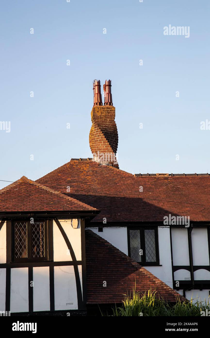 Twisted Brick Chimney stack su una proprietà residenziale staccata contro un cielo blu Foto Stock