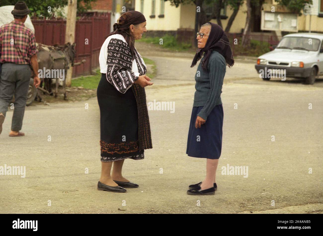 Arges County, Romania, circa 2002. Donne anziane che parlano sulla corsia del villaggio, una di loro indossa un costume tradizionale popolare. Foto Stock
