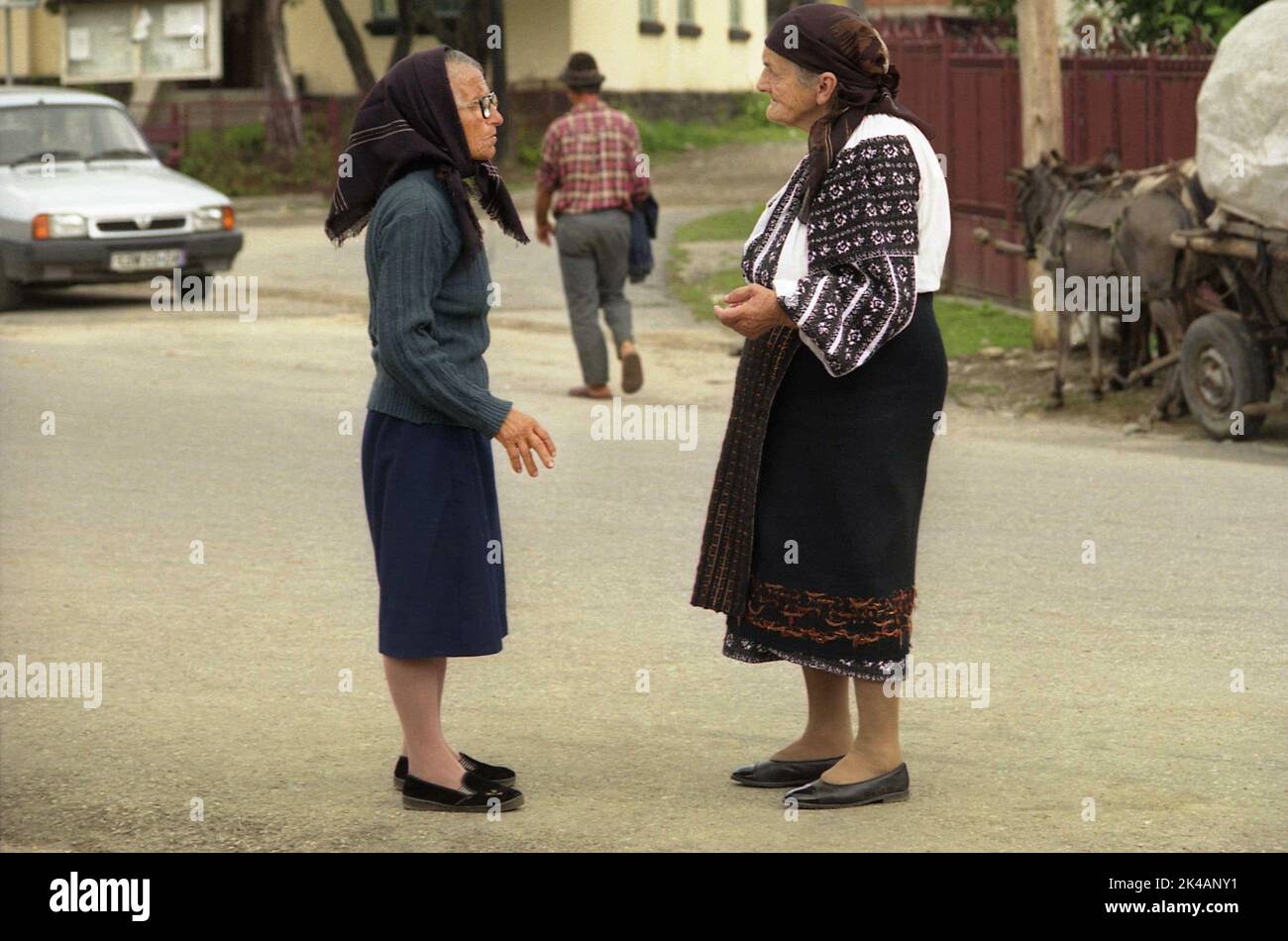Arges County, Romania, circa 2002. Donne anziane che parlano sulla corsia del villaggio, una di loro indossa un costume tradizionale popolare. Foto Stock