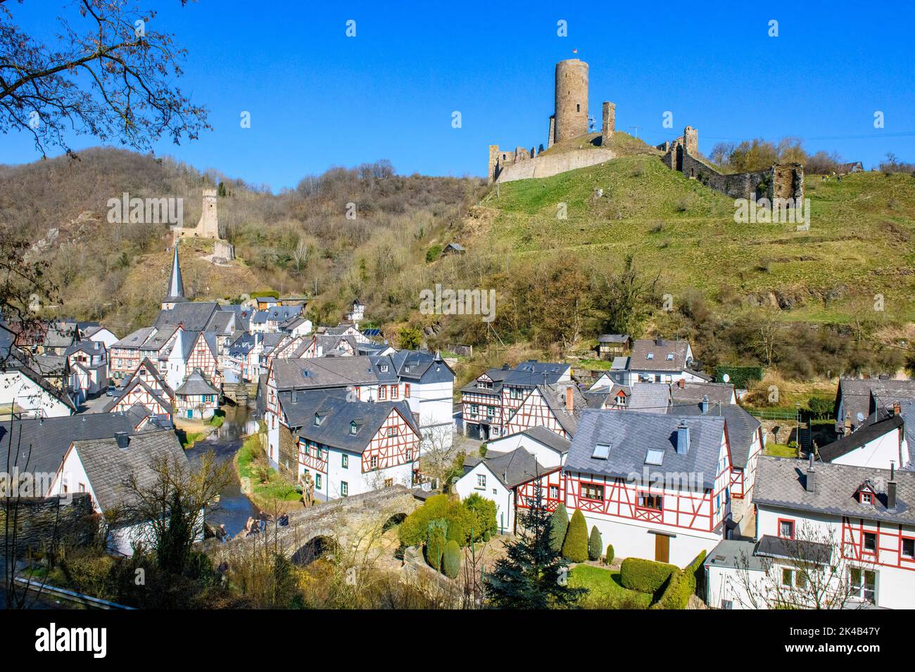 Vista dello storico villaggio di Eifel Monreal con case a graticcio e di fronte ponte inferiore sul fiume Elz Elzbach, in background rovina sinistra Foto Stock