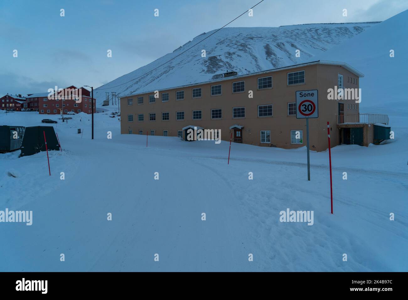 Primo piano di ingresso a bordo di un edificio giallo abbandonato circondato dalla neve a Longyearbyen, Svalbard Foto Stock