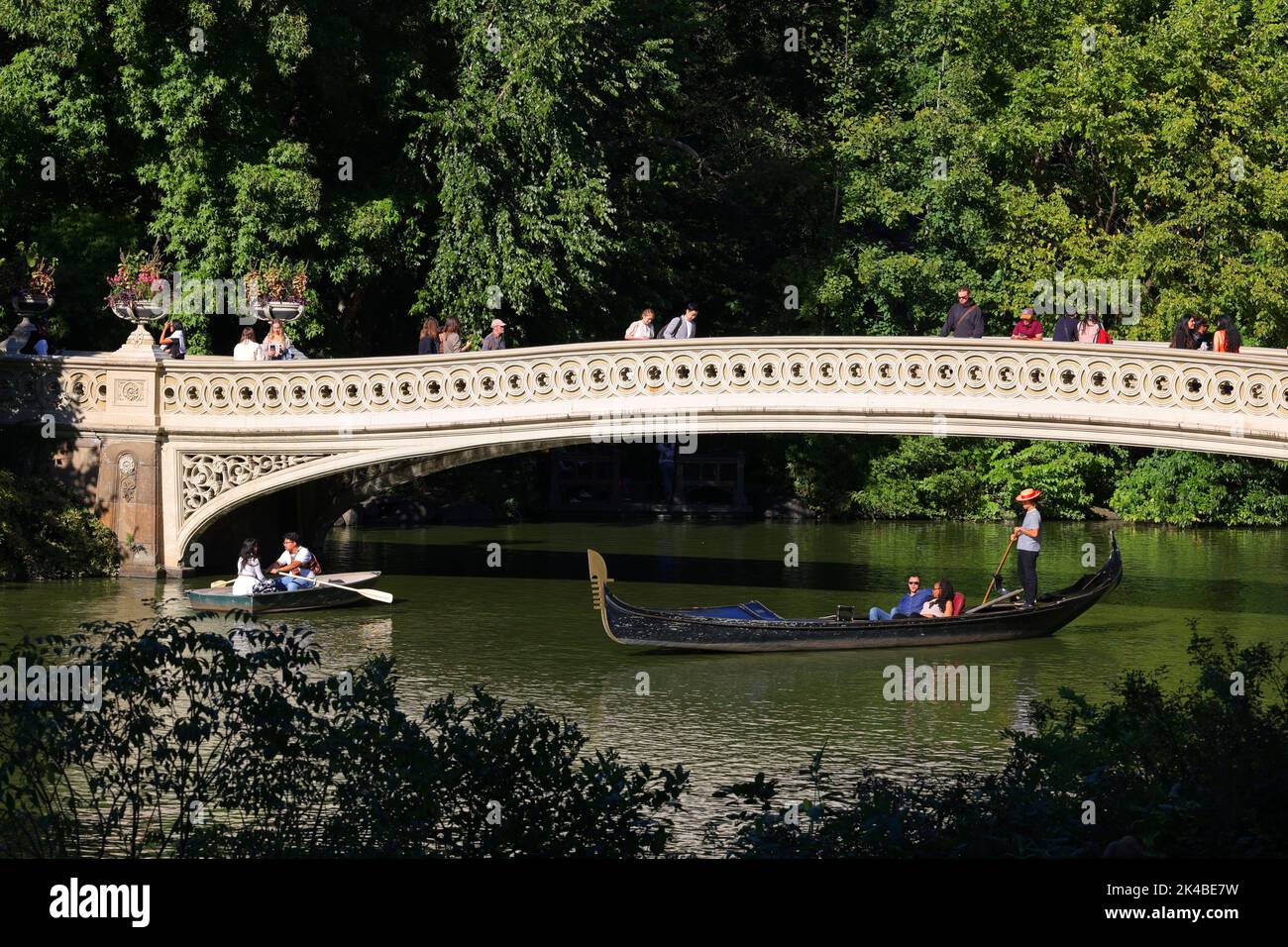 Una gondola passa sotto il Bow Bridge a Central Park, New York. Il ponte di Bow si estende sul lago che collega Bethesda Terrace al Ramble Foto Stock