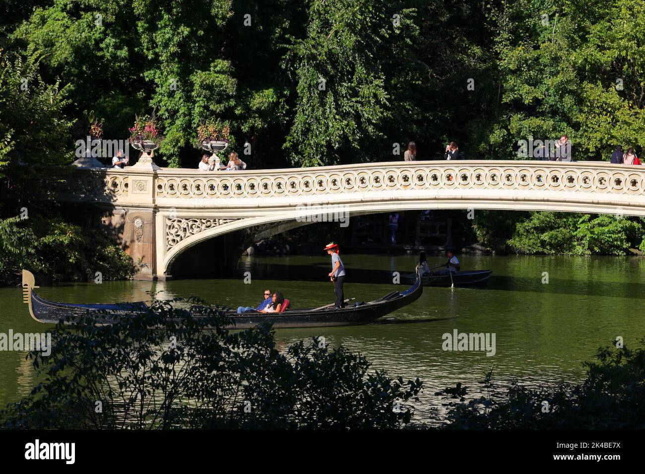 Una gondola passa sotto il Bow Bridge a Central Park, New York. Il ponte di Bow si estende sul lago che collega Bethesda Terrace al Ramble Foto Stock