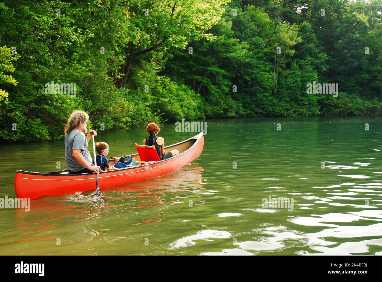 Una famiglia con un bambino piccolo esplora un lago e ruscello in una canoa su una bella vacanza estiva dahy Foto Stock