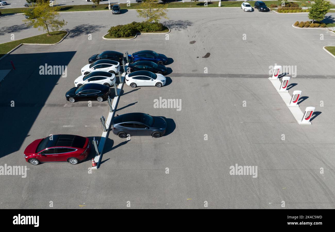 Vista aerea sopra una stazione di ricarica Tesla piena di auto Tesla colorate situate presso una concessionaria, i Supercharger Tesla sono considerati vuoti. Foto Stock