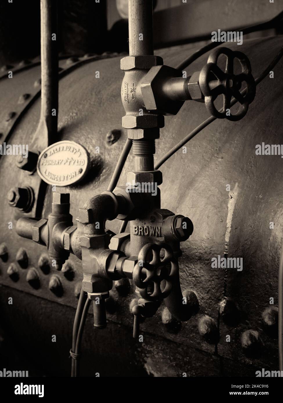Vecchio impianto di caldaia d'epoca e antico per attrezzature agricole. Tono mono. Tubi e maniglie in acciaio e rivetti enormi sulla caldaia Foto Stock