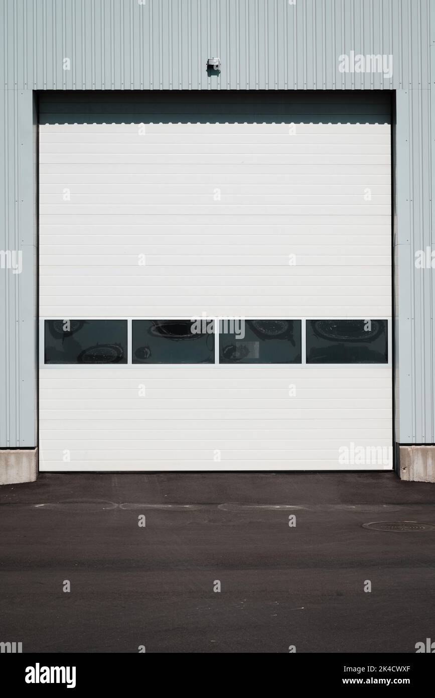 Un'immagine verticale di una porta di garage bianca in una parete blu Foto Stock