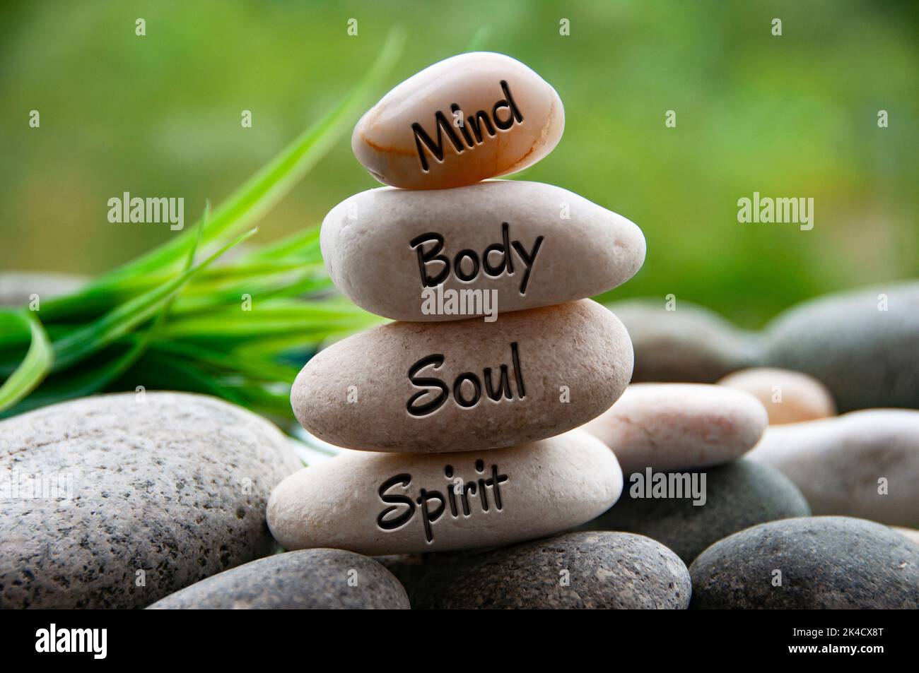 Mente, corpo, anima e Spirito parole incise su pietre zen con sfondo naturale sfocato. Copiare spazio e concetto zen. Foto Stock
