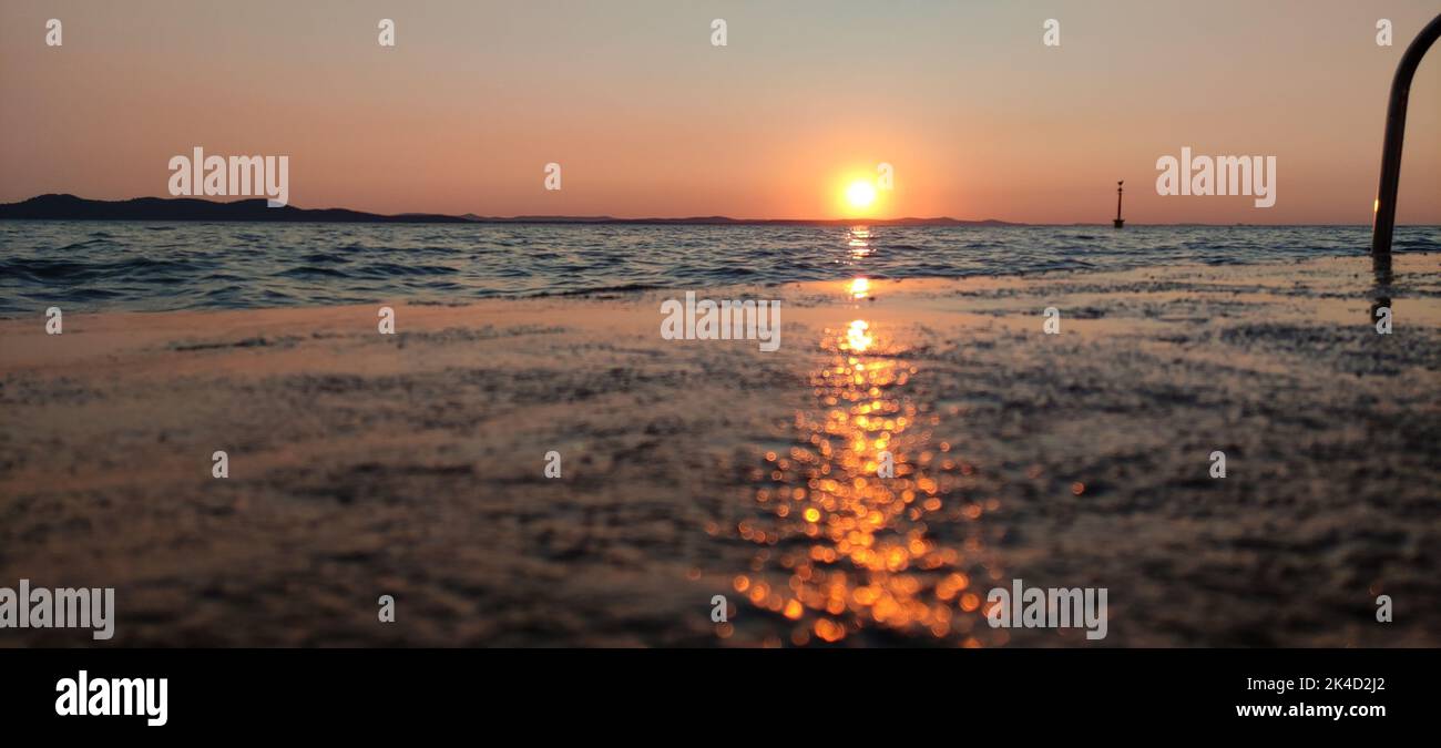 Uno scatto panoramico di un bel cielo tramonto sul lago di Zara, Croazia Foto Stock