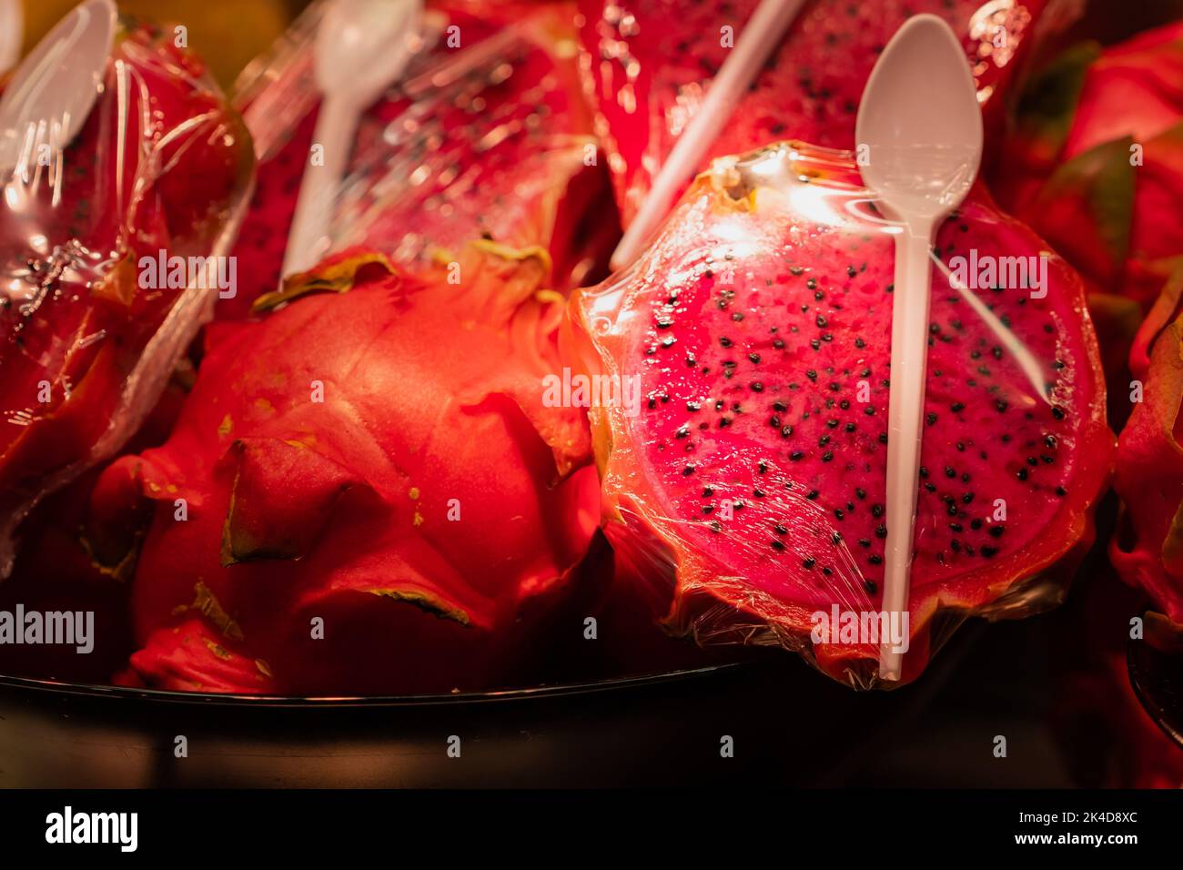 Pitahaya, frutto del drago tagliato a metà e avvolto in plastica trasparente al mercato Boqueria di Barcellona (Spagna), concetto gastronomico, selettivo apro Foto Stock