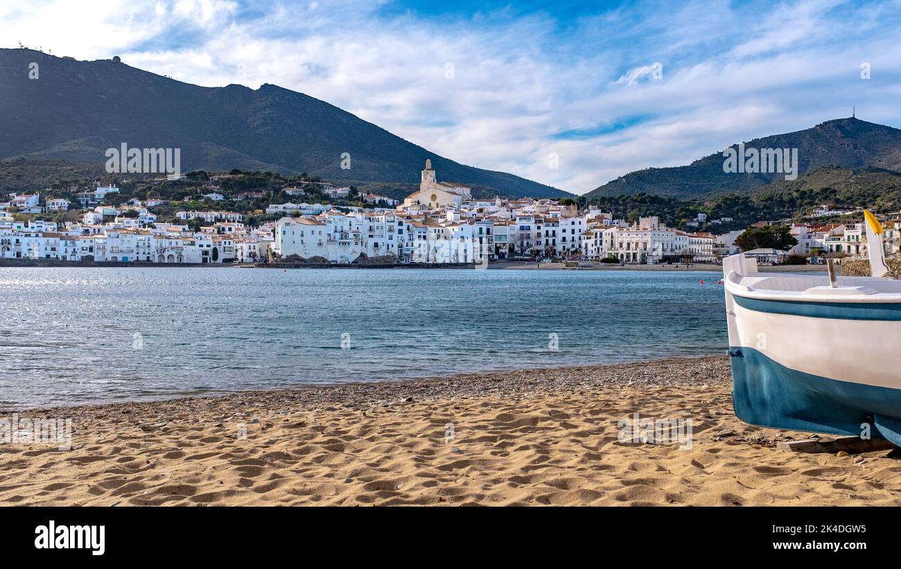 Vista della città di Cadaques, Spagna, con una barca da pesca in primo piano. Preso in inverno durante un pomeriggio di festa di inverno soleggiato con un certo unrecogniz Foto Stock