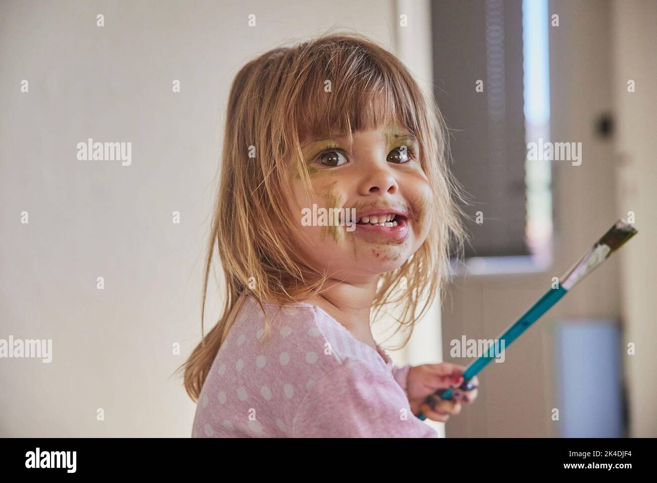 Il bambino affascinante disegna e macchia tutto con le pitture Foto Stock