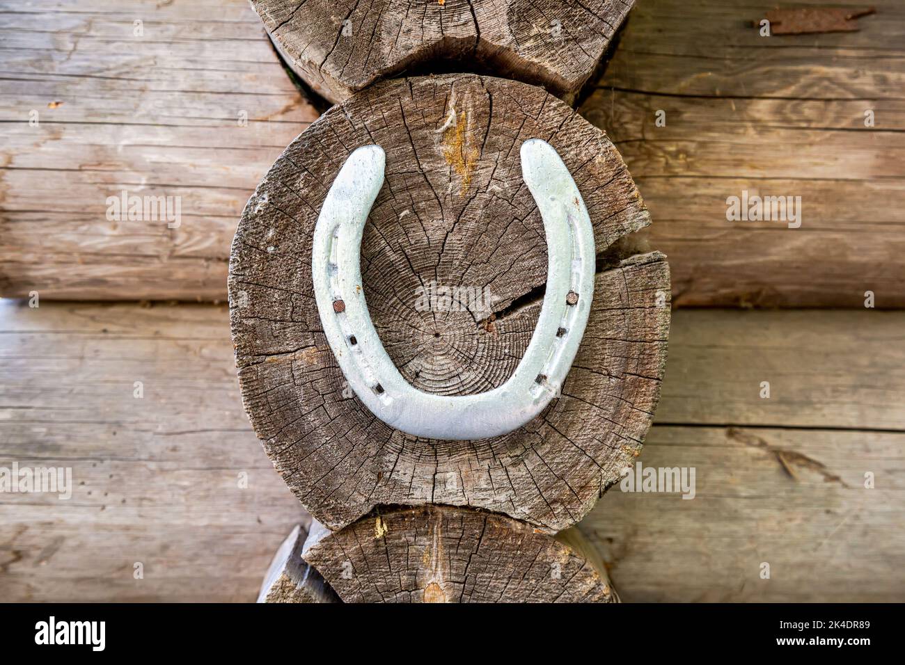 Vecchio ferro di cavallo di metallo appeso al muro di una casa di legno Foto Stock