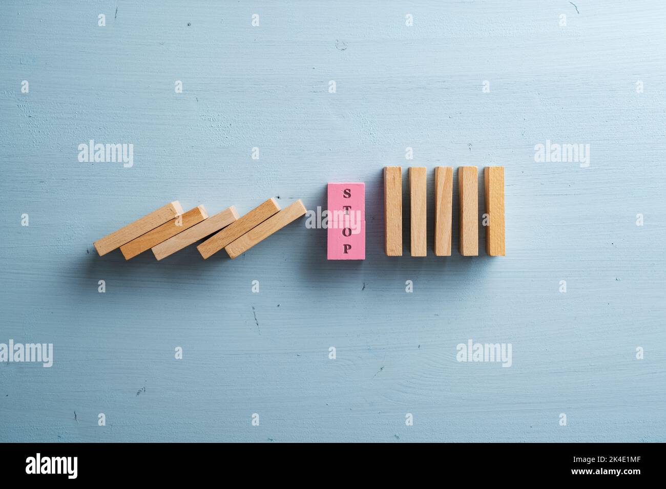 Sosta di parola su una pila di blocchi di legno rosa che interrompono il collasso dominos in un'immagine concettuale di approccio proattivo alla situazione critica. Oltre il pas Foto Stock