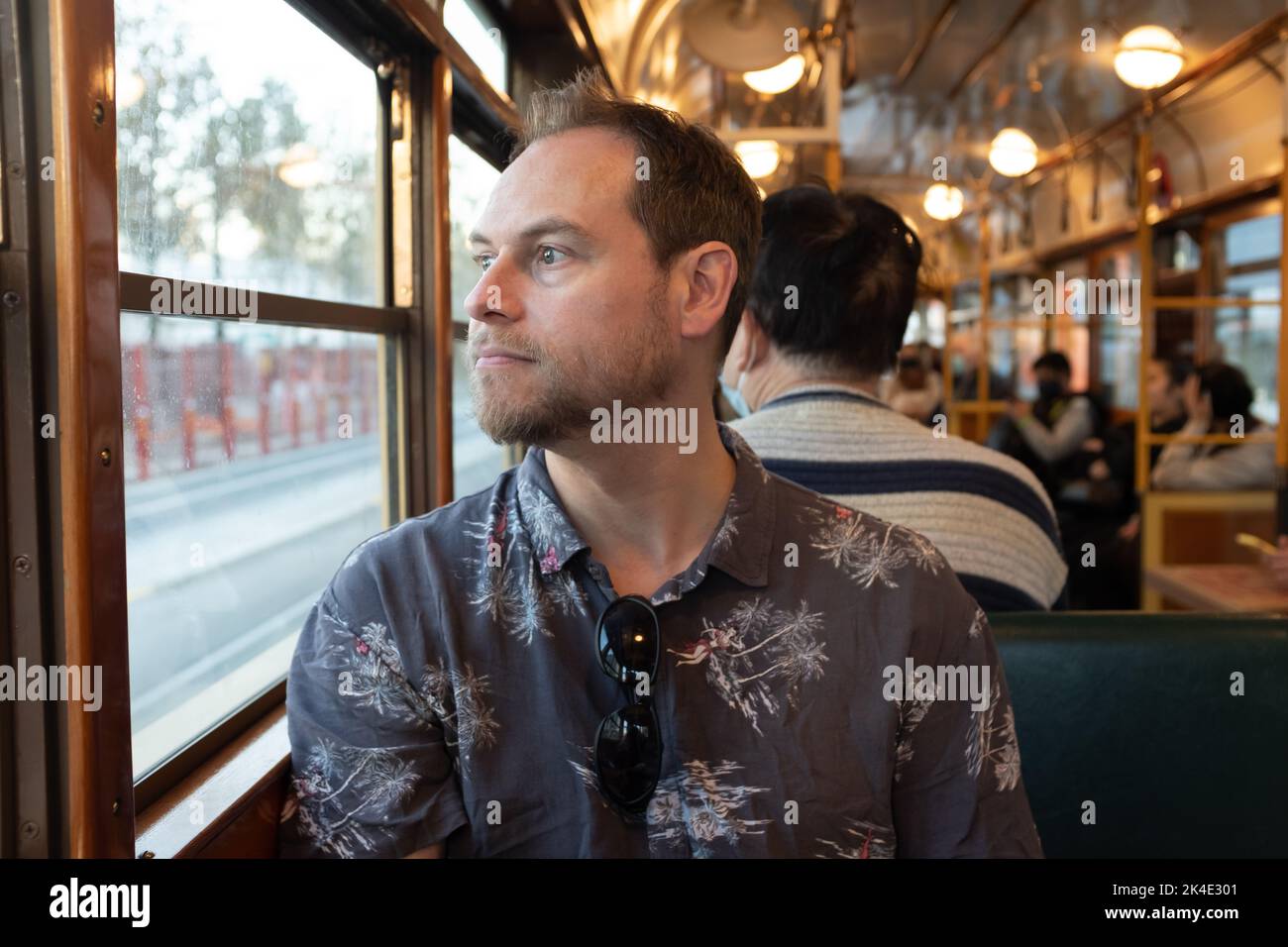 Un uomo seduto in un famoso tram storico di Melbourne W Class che guarda fuori dalla finestra Foto Stock