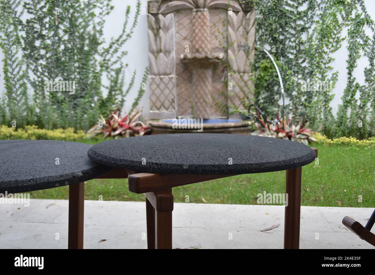 terrazza all'aperto con tavoli da caffè all'aperto, piano in pietra e base in legno massiccio o legno duro Foto Stock
