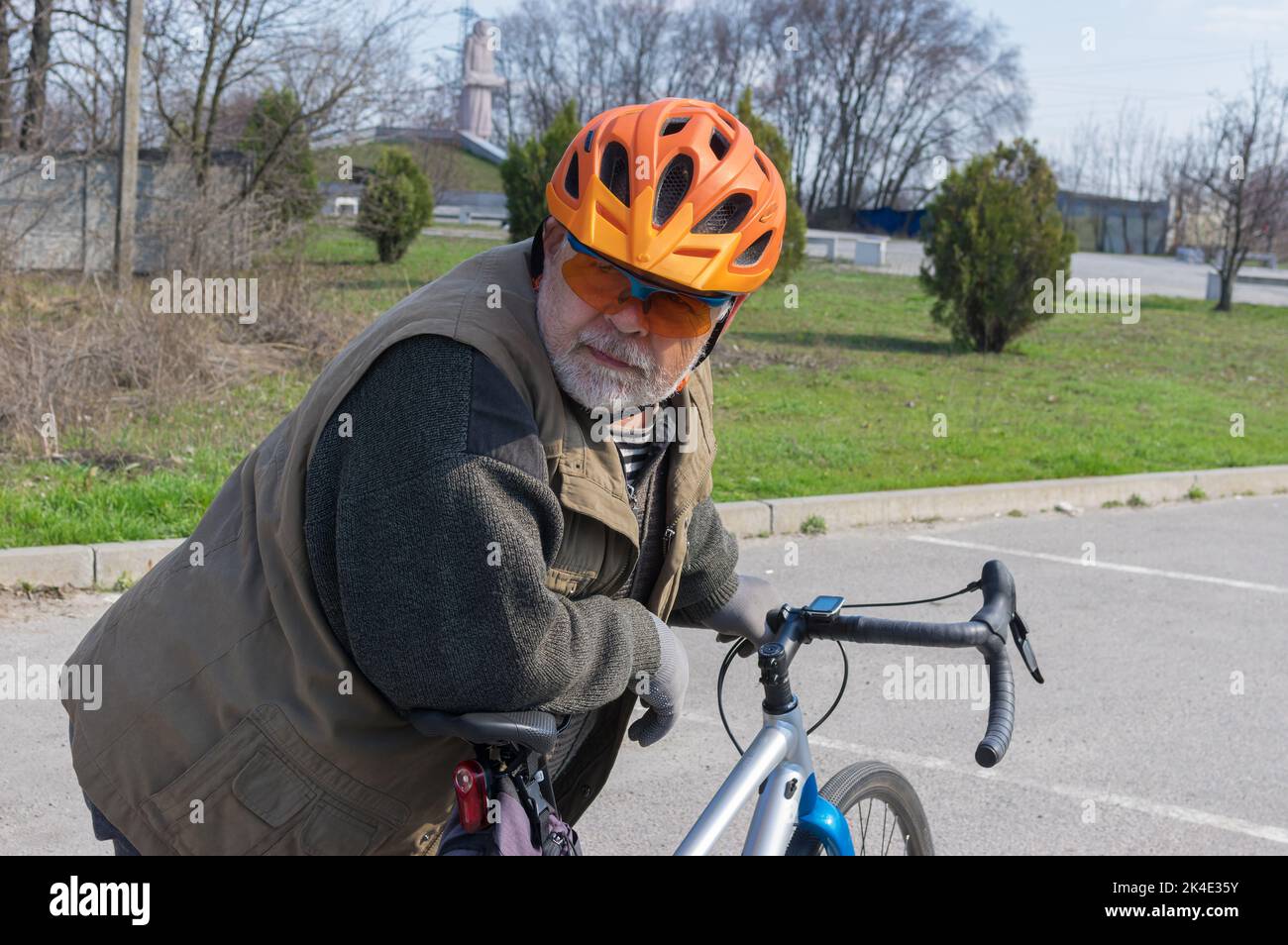 Bel ritratto all'aperto di un uomo anziano ucraino caucasico, barbuto, che guarda quando si prepara a guidare su una bicicletta ghiaiosa Foto Stock