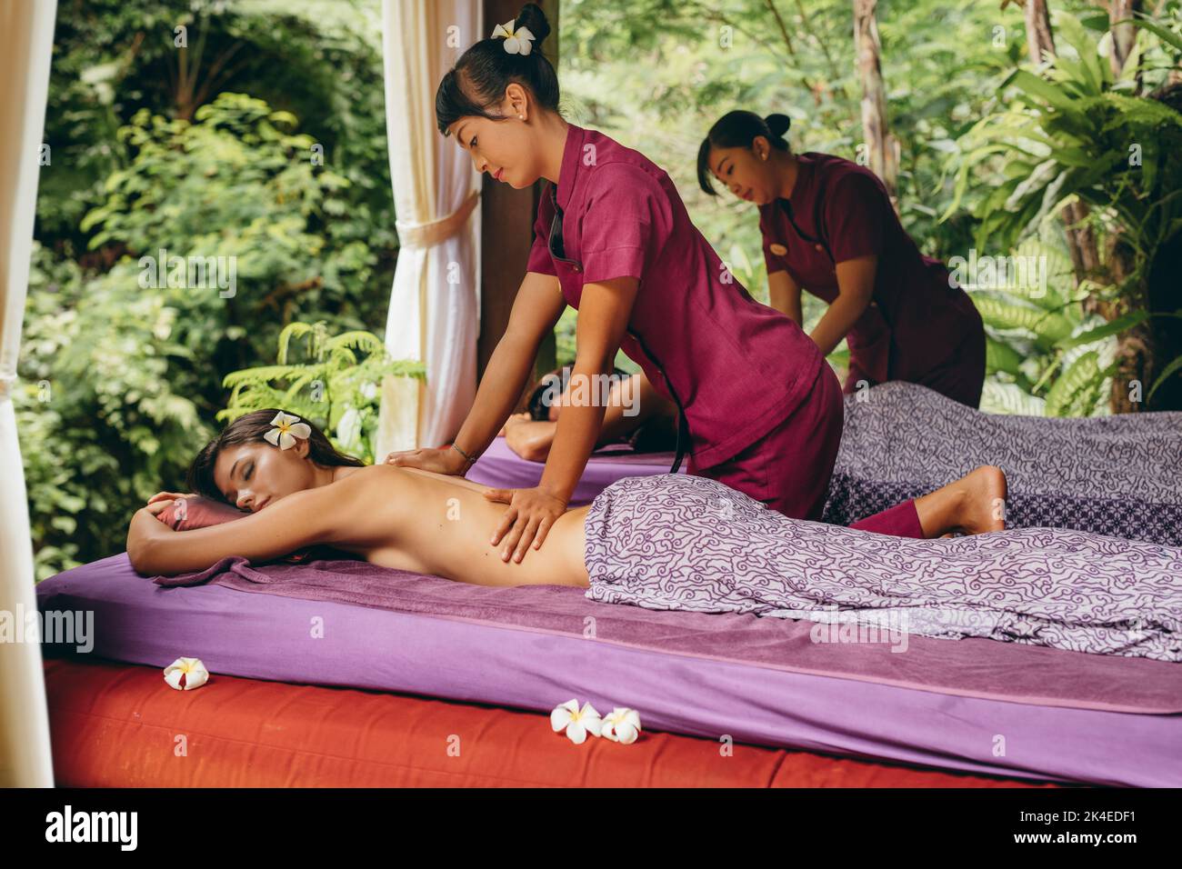 Foto dei giovani alla spa all'aperto e massaggio corpo al resort. Coppia con massaggio alla schiena presso il lussuoso centro termale del resort. Foto Stock