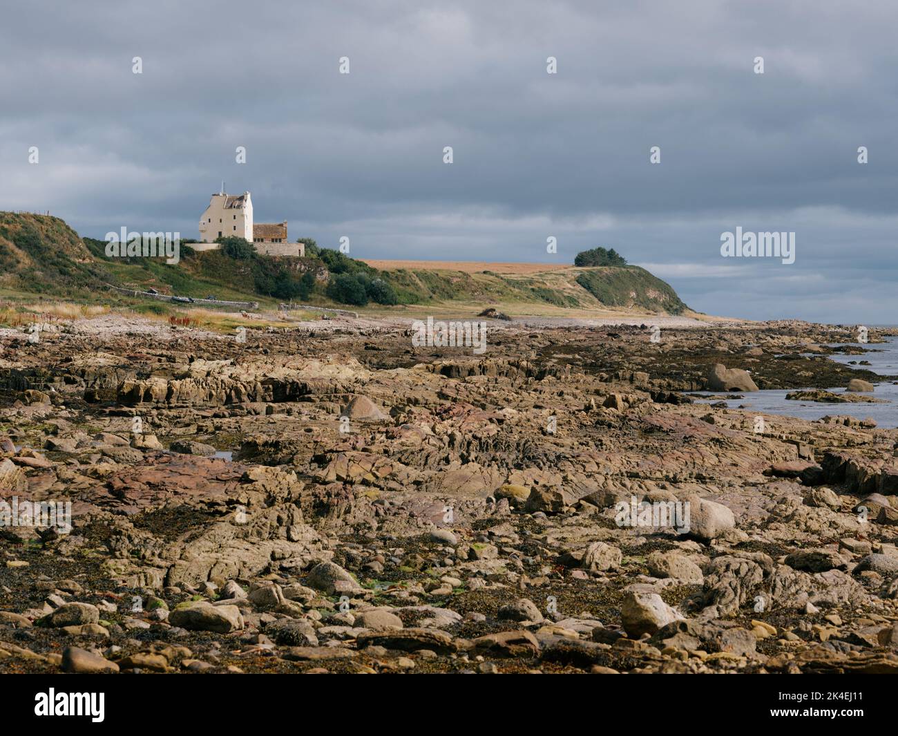 Ballone Castle / Tarbat Castle e rockpool bassa marea costeggia la costa della penisola di Tarbat, Tain, Ross & Cromartey in Highland Scozia UK Foto Stock