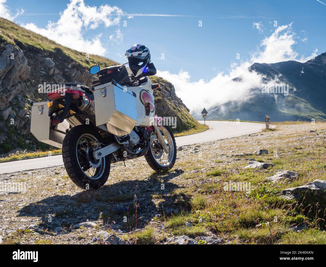 Una moto avventura con grandi casse in alluminio è parcheggiata presso un passo di montagna nelle alpi europee. Vista posteriore, vista ad angolo basso Foto Stock