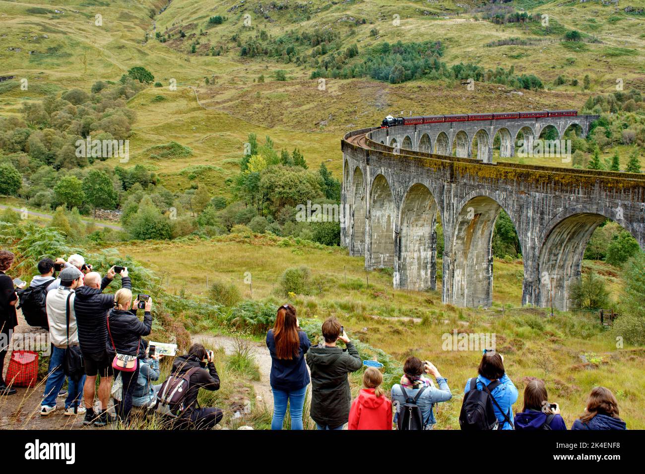 TRENO A VAPORE JACOBITE GLENFINNAN VIADOTTO SCOZIA TURISTI E SPETTATORI ALL'ARRIVO DEL TRENO A VAPORE E DELLE CARROZZE Foto Stock