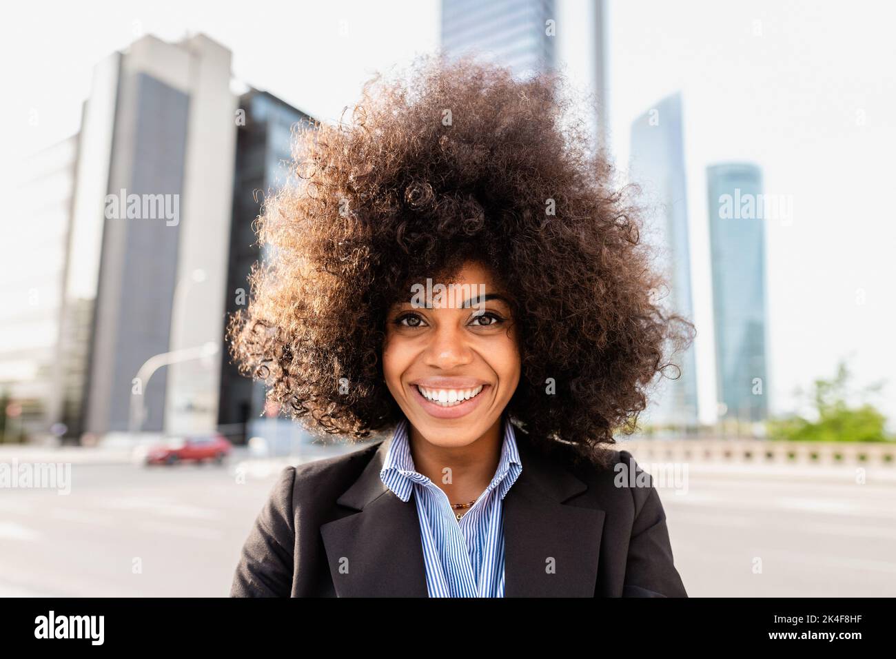 Donna d'affari che si diverte guardando davanti alla telecamera - Vista urbana e grattacieli sullo sfondo Foto Stock