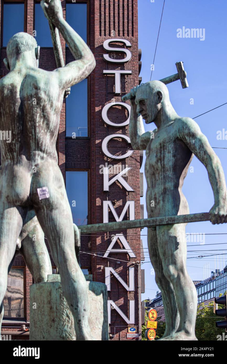 Grande magazzino Stockmann dietro la scultura Kolmen sepän patsas a Helsinki, Finlandia Foto Stock