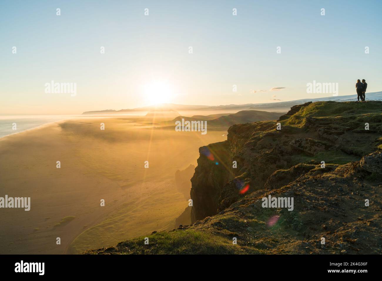 Coppia sulla scogliera al tramonto della penisola di Dyrholaey, vicino a Vik, Islanda del Sud (Sudurland), Islanda Foto Stock