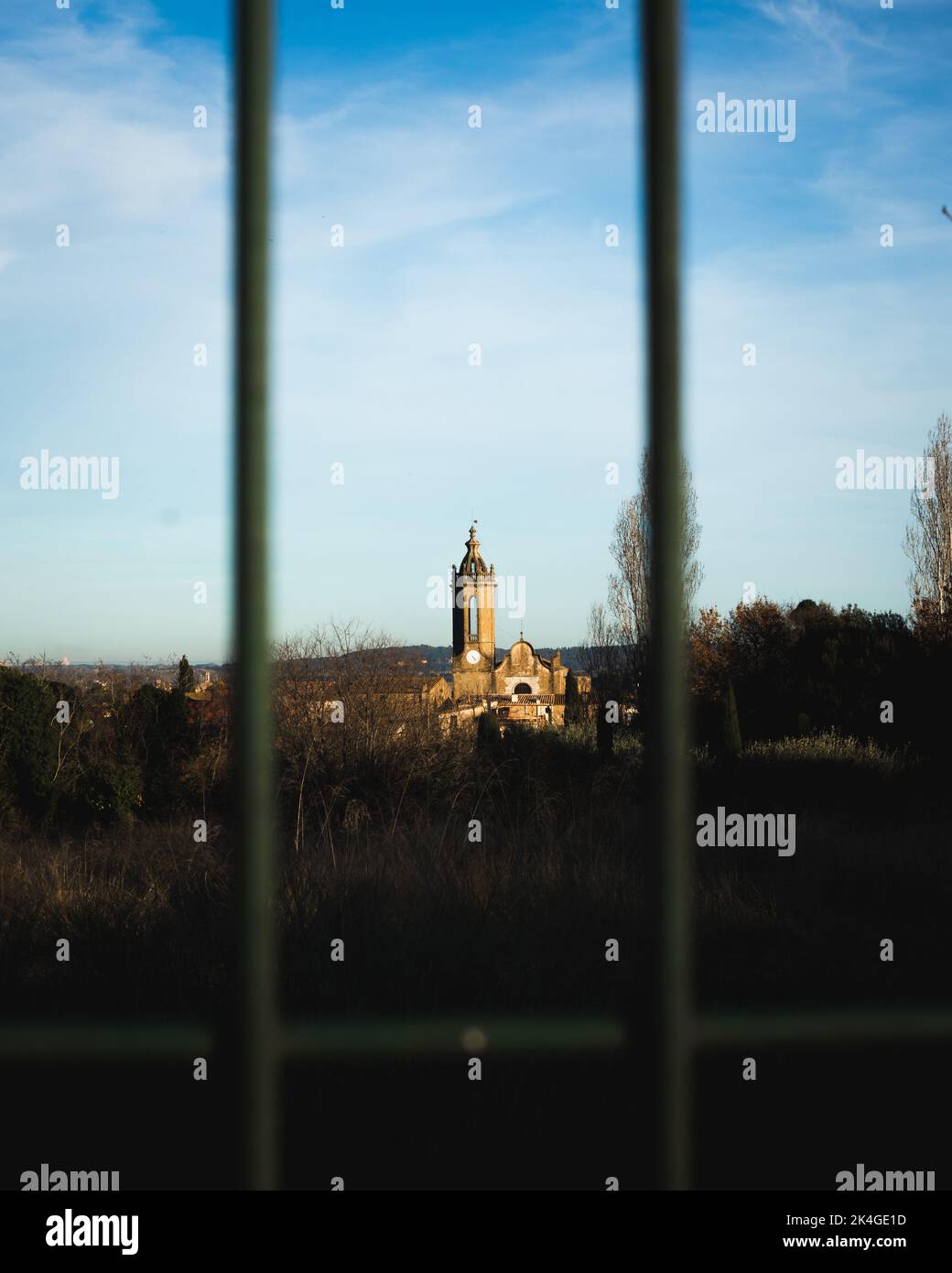 Una vista di una vecchia chiesa lontano attraverso una recinzione Foto Stock