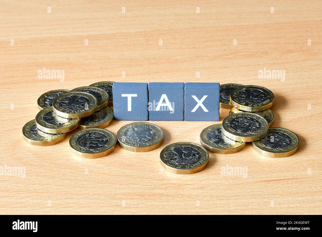Tassa di parola su piccoli blocchi di pietra circondati da monete britanniche da una libbra. Nessuna gente. Foto Stock