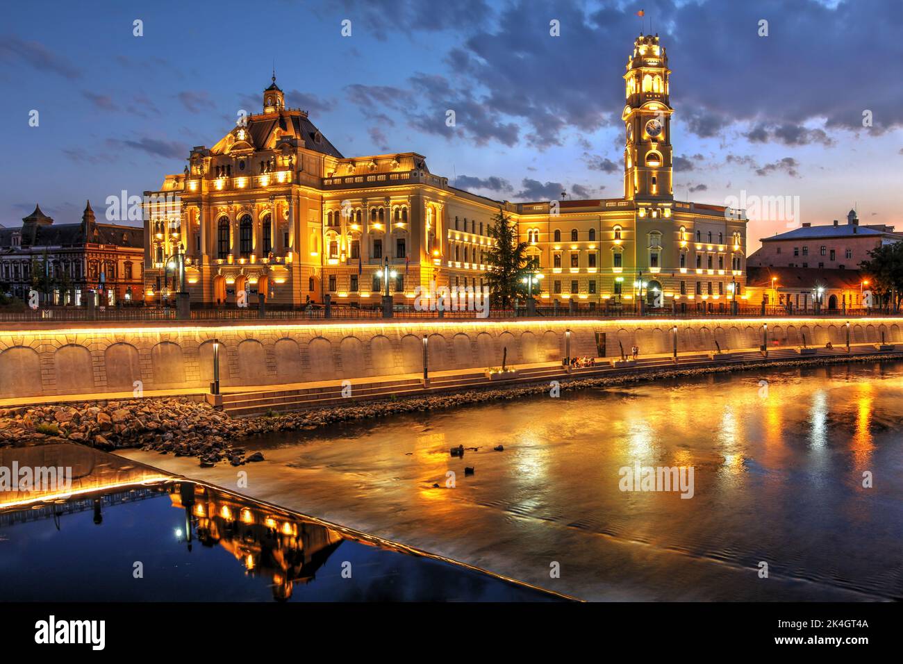 Palazzo del Municipio in stile eclettico a Oradea, in Romania, rispecchiava di notte il fiume Rapid Cris (Crisul Repede). Foto Stock
