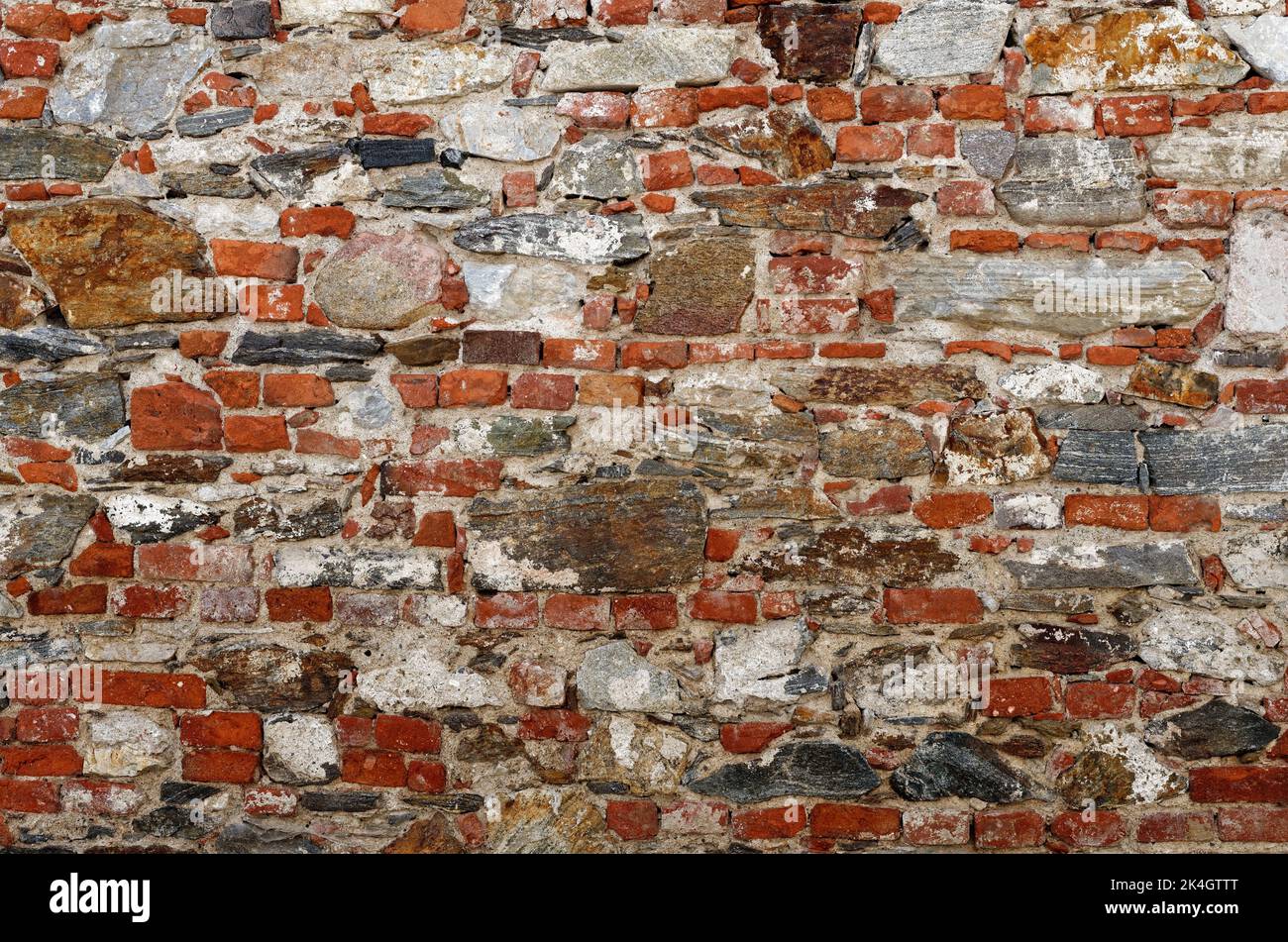 Struttura di vecchio muro costruito di mattoni rossi e pietre irregolari Foto Stock