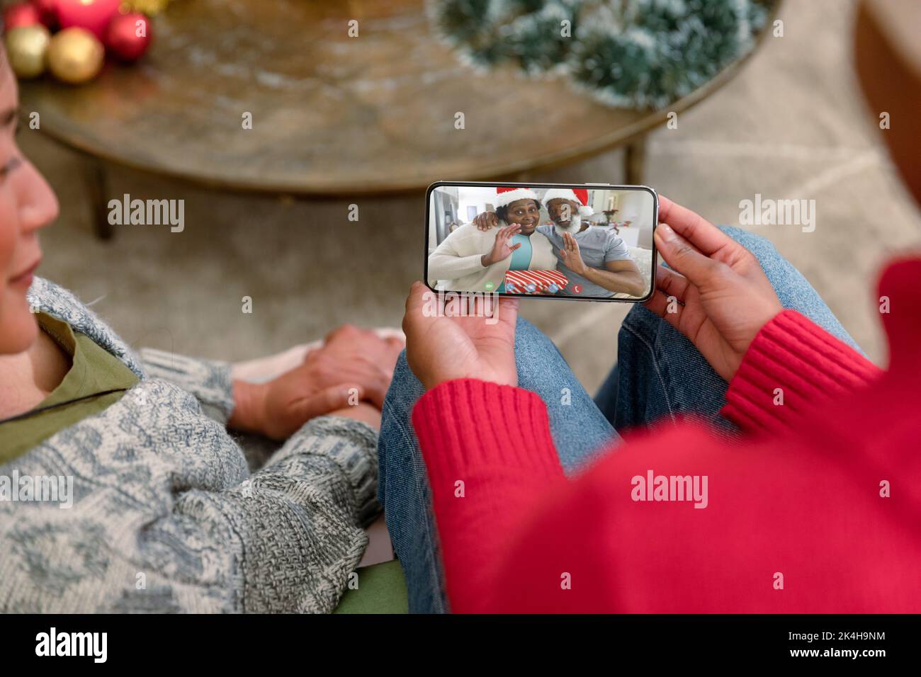 Amici biraciali su smartphone videochiamata di natale con coppia senior. natale, festa e tecnologia di comunicazione. Foto Stock