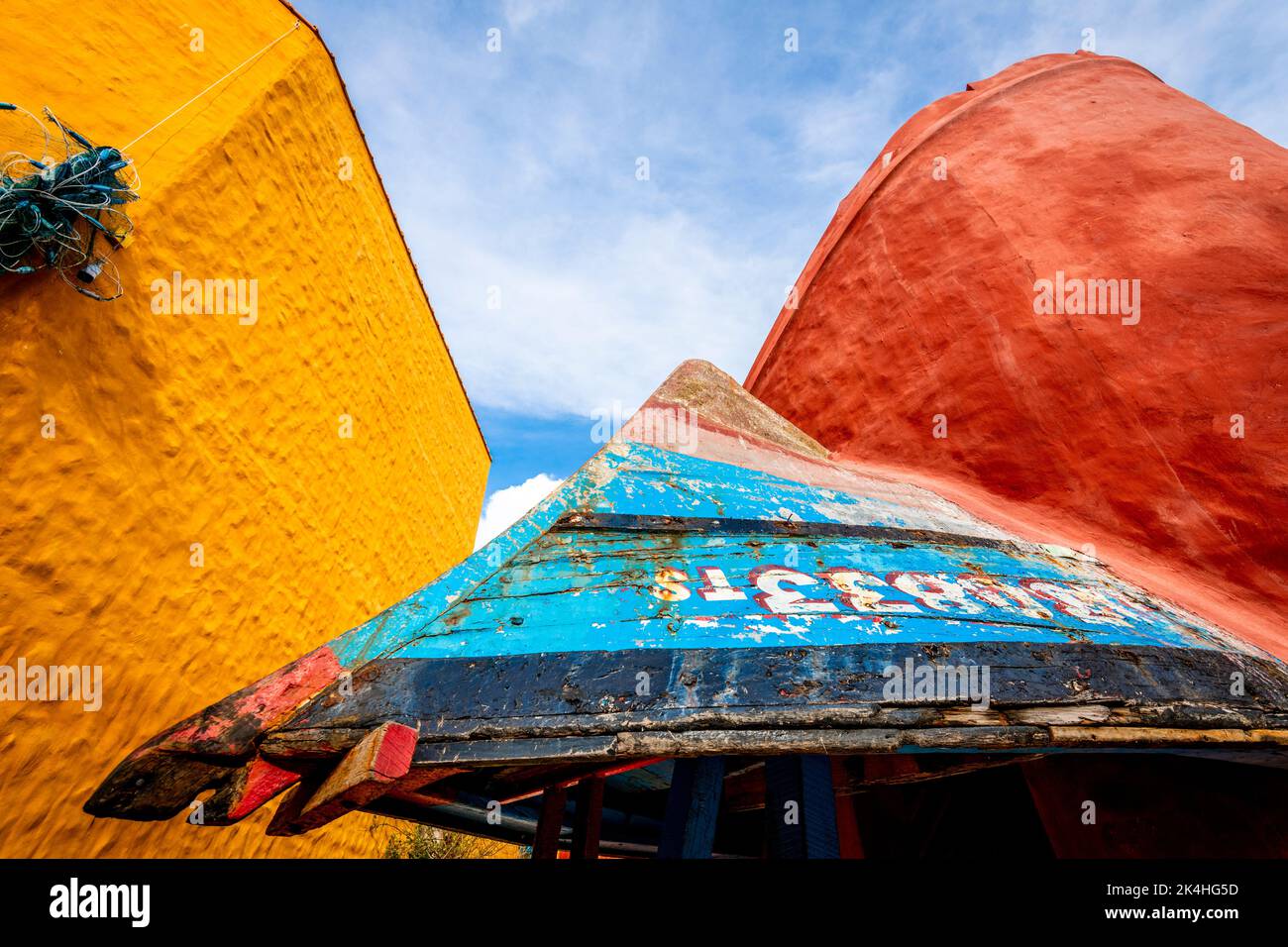 Un vecchio peschereccio capovolto fa ora parte di un edificio in questa fotografia astratta di due edifici di colore diverso. Foto Stock