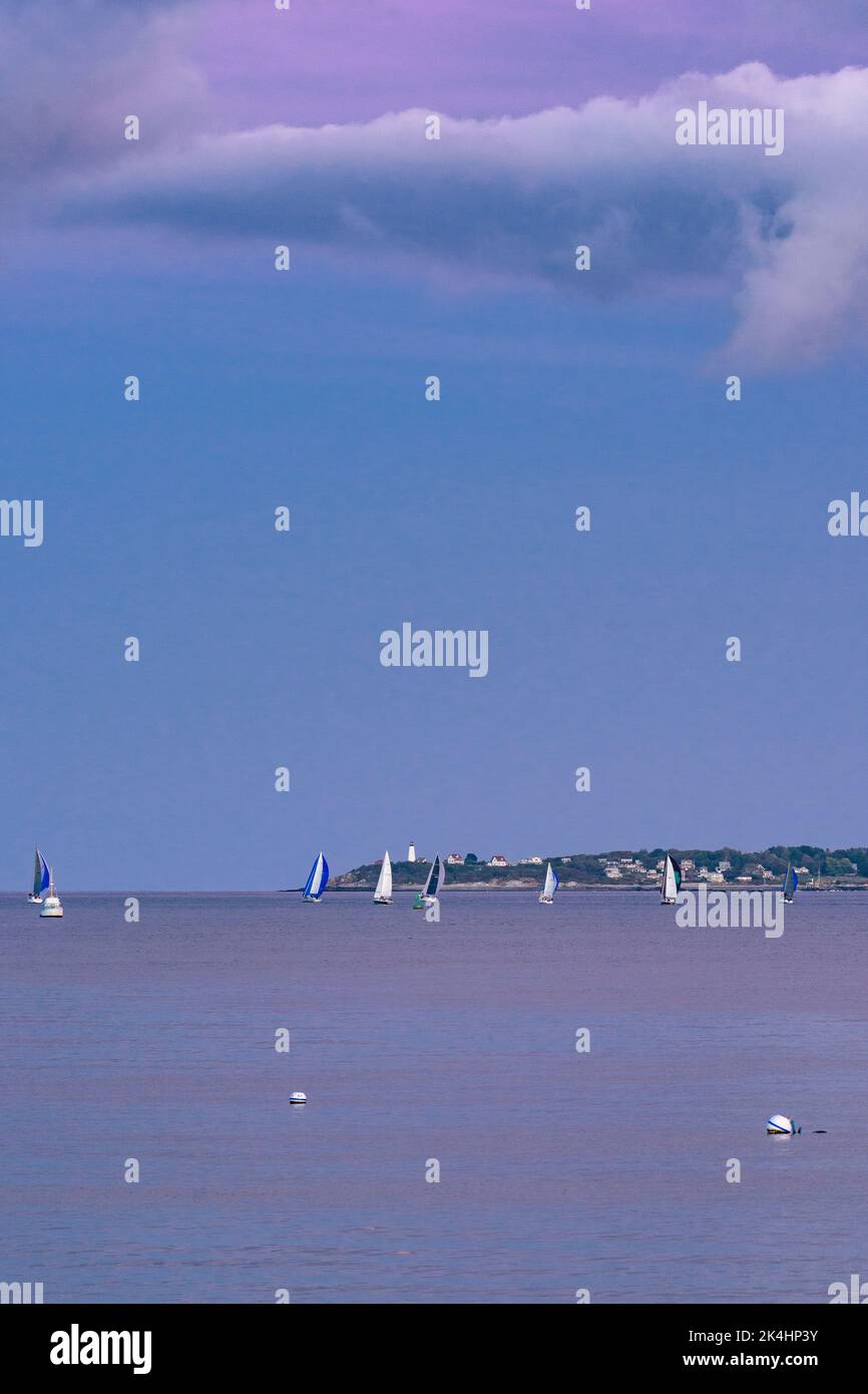 Barche a vela a vela a vela con Faro con nuvole rosa che si riflettono nel mare Foto Stock