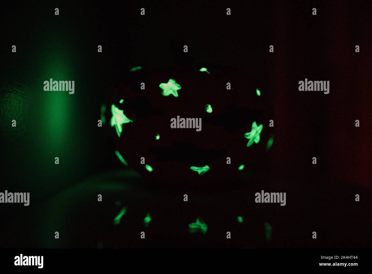 piccola luce nella zucca scura con stelle dipinte in verde Foto Stock