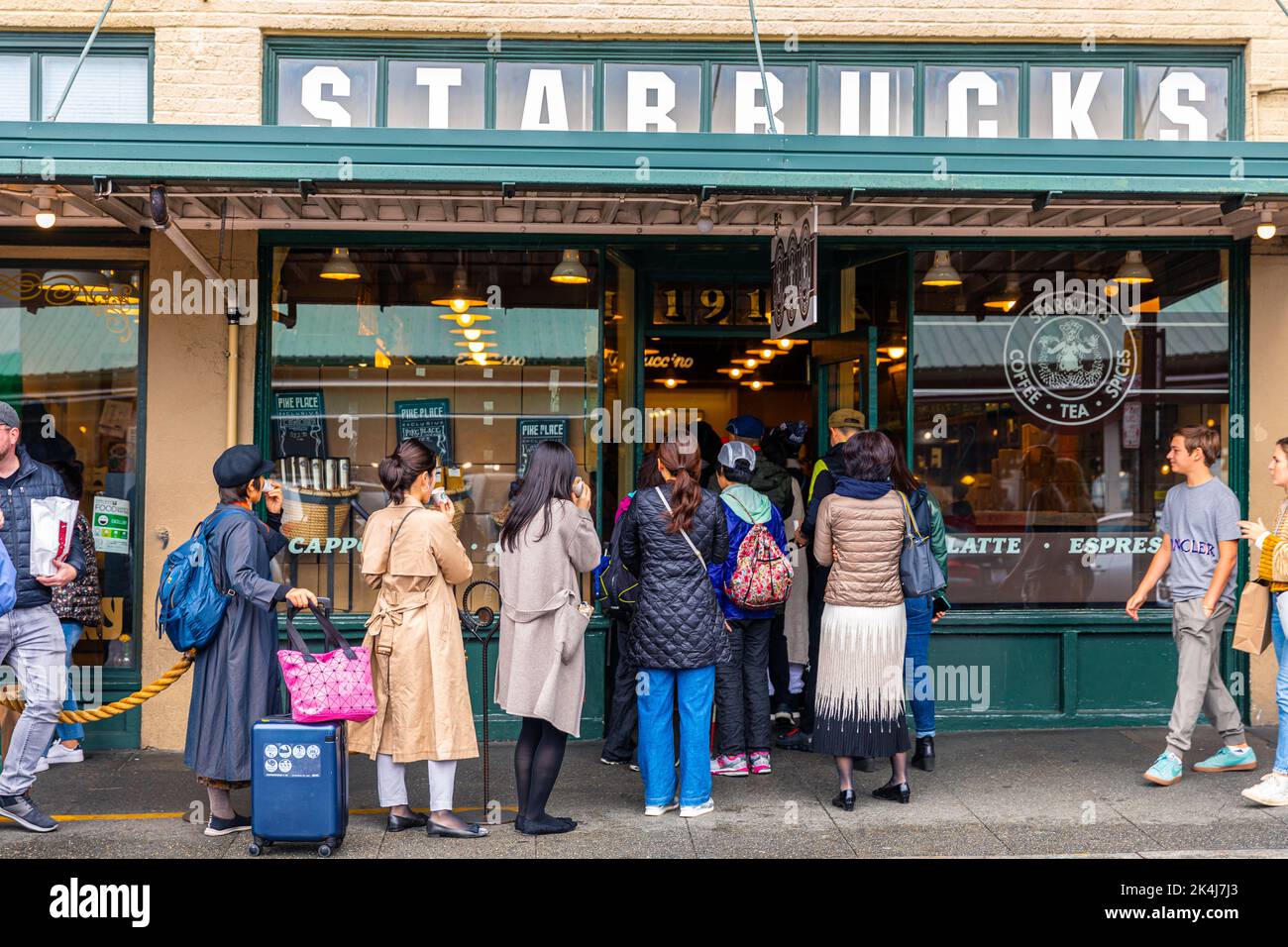 Seattle, Washington, USA - 9 ottobre 2019: Persone che aspettano sul sentiero in lunga coda per ordinare all'interno del primo Starbucks, il più classico e popolare Foto Stock