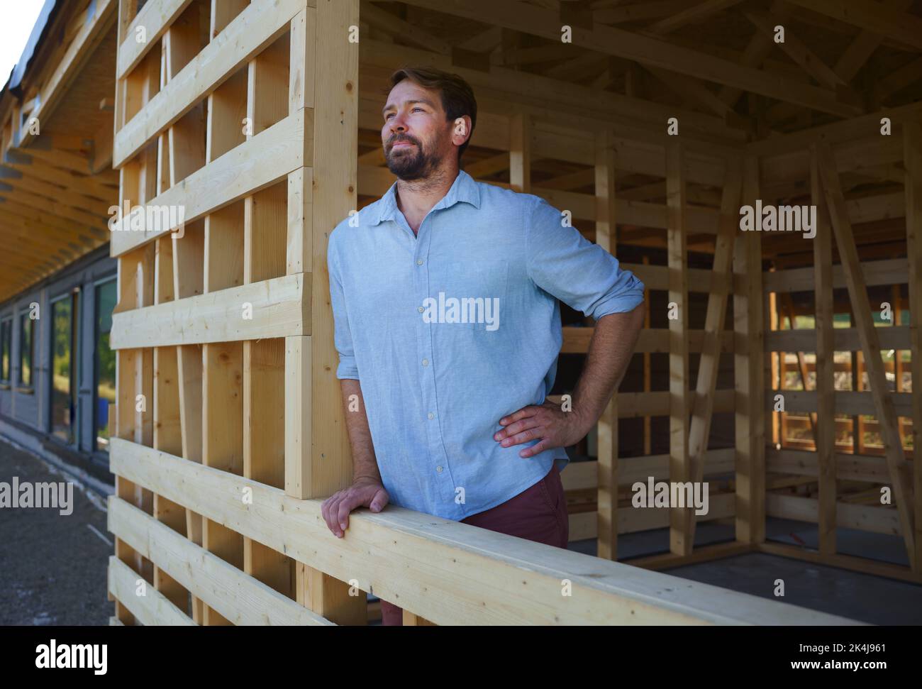 Uomo che guarda fuori dalla casa incompiuta, costruzione di eco-casa ecologica rinnovabile a basso consumo energetico sostenibile in legno . Foto Stock