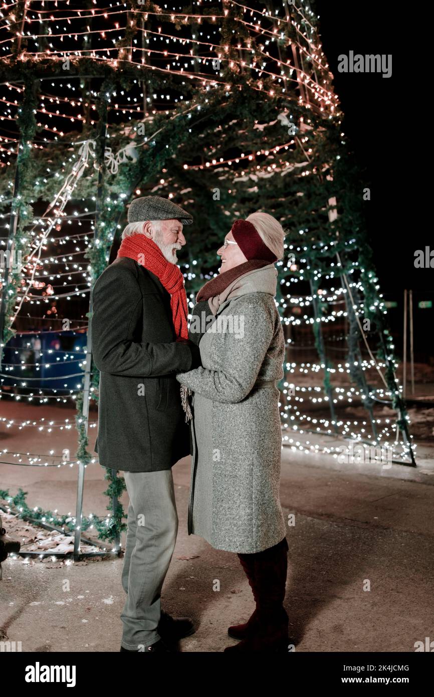 Coppia anziana innamorata in piedi di fronte alle decorazioni festive Foto Stock