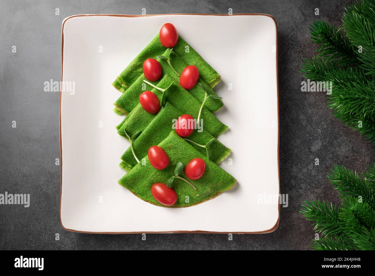 Antipasto a forma di albero di Natale di frittelle verdi sottili su piatto bianco Foto Stock