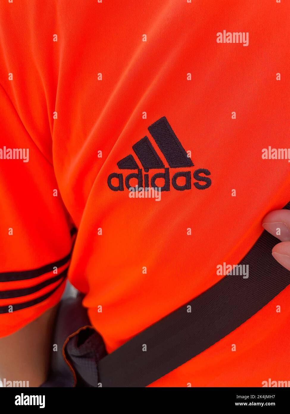 Tyumen, Russia-30 agosto 2022: Logo Adidas su T-shirt arancione. Adidas è una multinazionale tedesca per la produzione di abbigliamento e calzature Foto Stock